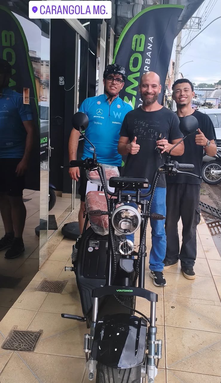 Cliente recebendo veículo elétrico preto na loja Voltzmob em Carangola