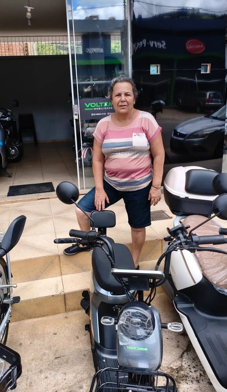 Cliente com seu veículo elétrico em frente à loja Voltzmob em Carangola